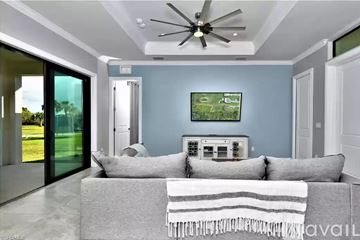 Naples apartment for rent - A modern living room with a grey sofa and a ceiling fan.
