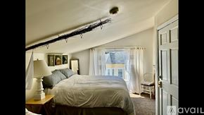 Newburyport apartment for rent - A bedroom with a bed, chair, and a window with curtains.