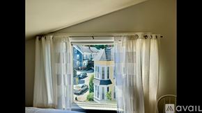 Newburyport apartment for rent - A window with curtains showing a street view with cars and buildings.