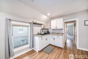 Grand Rapids apartment for rent - A kitchen with white cabinets and a window with grey curtains.
