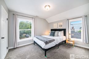Grand Rapids apartment for rent - A bedroom with a large bed and a window overlooking a green area.