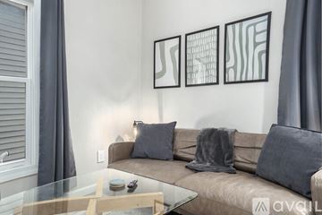 Grand Rapids apartment for rent - A living room with a couch, a glass table, and three abstract paintings on the wall.