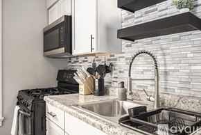 Grand Rapids apartment for rent - A kitchen with a black microwave above the stove and a white sink.