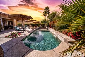 Palm Desert house for rent - A pool surrounded by palm trees and flowers at sunset.