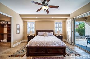 Palm Desert house for rent - A bedroom with a large bed and a ceiling fan.