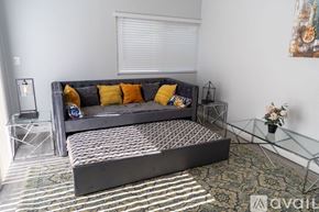 Fullerton house for rent - A grey couch with yellow pillows sits in a room with a glass table and a painting on the wall.