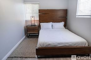 Fullerton house for rent - A bedroom with a large bed and a small table with a lamp on it.