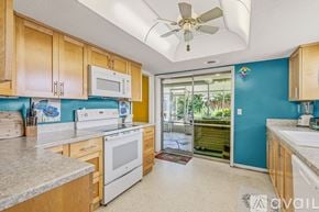 Ormond Beach house for rent - A bedroom with a bed, a ceiling fan, and a television mounted on the wall.
