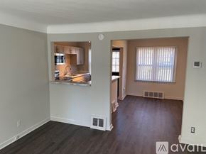 Detroit apartment for rent - A living room with a kitchen in the background and a window with blinds.