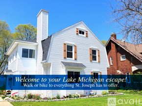 St. Joseph house for rent - A white house with a blue banner that says "Welcome to your Lake Michigan escape! Walk or bike to everything St. Joseph has to offer."