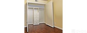 Dallas apartment for rent - A bedroom with a white closet and wooden floors.