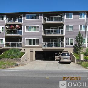 Seattle apartment for rent - A grey apartment building with a car parked in front.