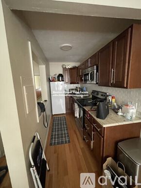 Boston apartment for rent - A kitchen with wooden cabinets and a checkered mat on the floor.
