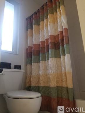 Miami house for rent - A toilet with a shower curtain in front of it.