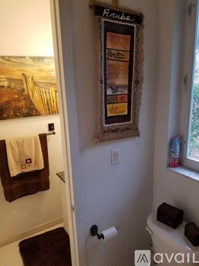 Miami house for rent - A bathroom with a towel hanging on the door and a picture of a beach on the wall.