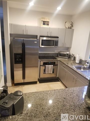 Miami house for rent - A kitchen with a granite countertop and stainless steel appliances.