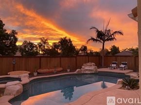 Oceanside house for rent - A pool surrounded by a wooden fence with a palm tree in the background.