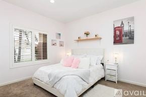 Oceanside house for rent - A bedroom with a large bed, a window with blinds, and a red telephone booth poster on the wall.