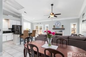 Oceanside house for rent - A kitchen with a dining table set up with chairs and a vase of flowers.