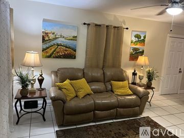 Tampa house for rent - A living room with a brown leather couch and two lamps.