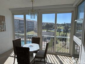 Fort Myers condo for rent - A balcony with a table and chairs overlooking a pool and a building.