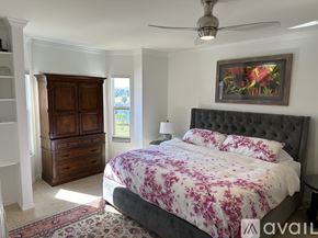 Fort Myers condo for rent - A bedroom with a large bed and a wooden wardrobe.