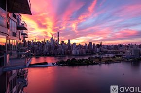 Queens house for rent - A city skyline at sunset with buildings and a body of water in the foreground.