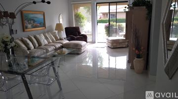 Rancho Mirage townhouse for rent - A living room with a glass table and a painting on the wall.