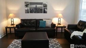 Tampa apartment for rent - A black leather couch with a blue pillow and two lamps on side tables.