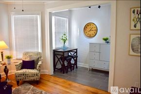Tampa apartment for rent - A living room with a chair, a table, a clock, and a cabinet.