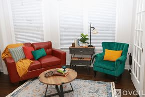 Tampa apartment for rent - A living room with a red couch, green armchair, and a wooden coffee table.
