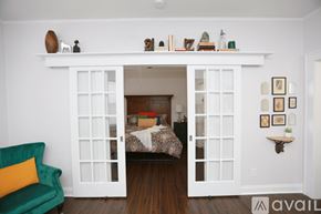 Tampa apartment for rent - A room with a white doorway leading to a bedroom, a green chair, and a shelf with various objects on it.