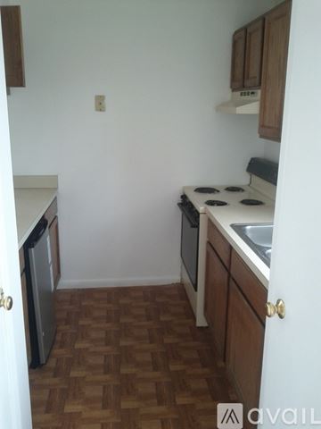 Bedford apartment for rent - A kitchen with a white counter top and wooden cabinets.