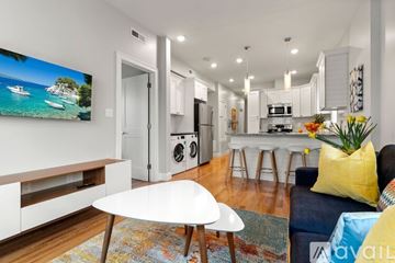 Boston apartment for rent - A modern living room with a white table and a painting of a beach scene on the wall.