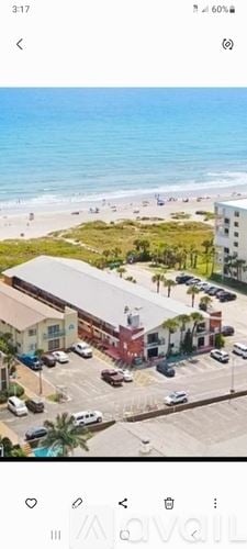 Cocoa Beach condo for rent - A beachfront view with a building and cars parked in front.