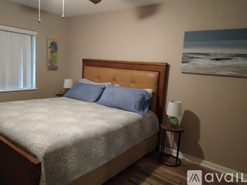 Cocoa Beach condo for rent - A bedroom with a bed, a nightstand with a lamp, and a painting on the wall.