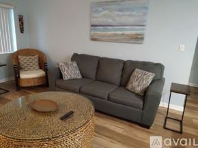 Cocoa Beach condo for rent - A living room with a grey couch, a wicker chair, and a coffee table.