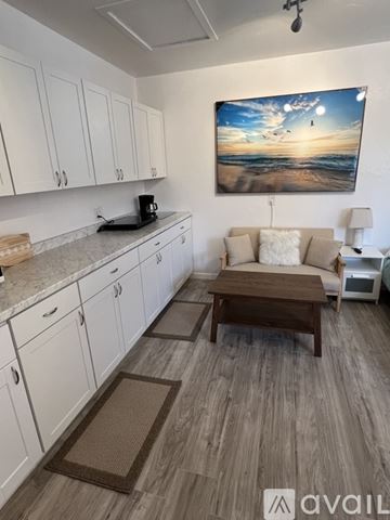 Marina apartment for rent - A kitchen with white cabinets and a painting of a beach scene on the wall.