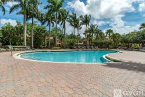 Royal Palm Beach condo for rent - A pool surrounded by palm trees and a brick patio.