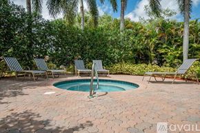 Royal Palm Beach condo for rent - A pool surrounded by palm trees and lounge chairs.