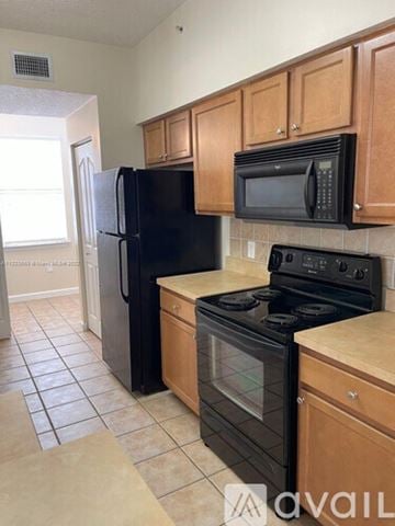 West Palm Beach condo for rent - A kitchen with black appliances and wooden cabinets.
