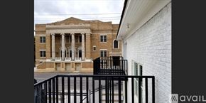 Dallas apartment for rent - A white brick building with a black railing in front.