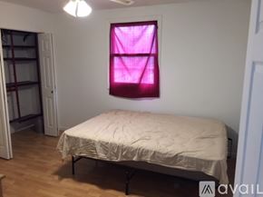 Chicago house for rent - A bedroom with a bed, a window with a pink curtain, and a wooden floor.