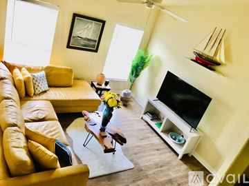 Venice apartment for rent - A living room with a yellow couch, a television, and a small table with a vase of flowers on it.