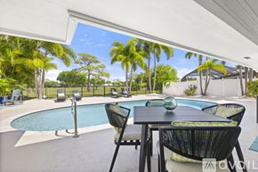 Jupiter apartment for rent - A patio with a table and chairs overlooking a pool.