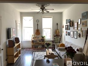 Chicago apartment for rent - A living room with a couch, a guitar, a fan, and a rug.