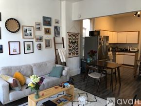 Chicago apartment for rent - A living room with a grey couch, a wooden coffee table, and a wall with framed pictures.