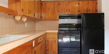Dallas apartment for rent - A kitchen with wooden cabinets and a black fridge.