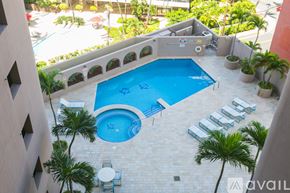 Honolulu condo for rent - A small pool surrounded by a balcony and palm trees.