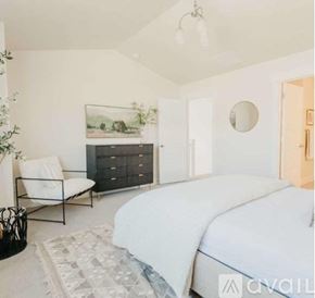 Lehi apartment for rent - A bedroom with a large bed, a chair, and a painting on the wall.
